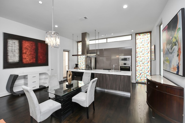 dining space with sink, dark hardwood / wood-style flooring, and an inviting chandelier