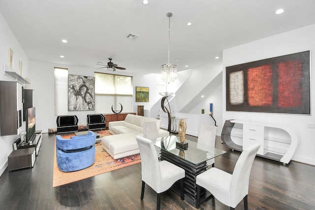 dining room with ceiling fan with notable chandelier and dark hardwood / wood-style flooring