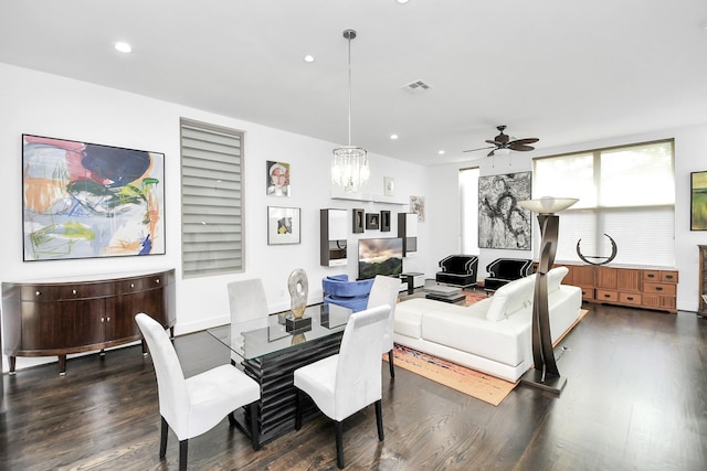 dining space featuring ceiling fan with notable chandelier and dark hardwood / wood-style flooring