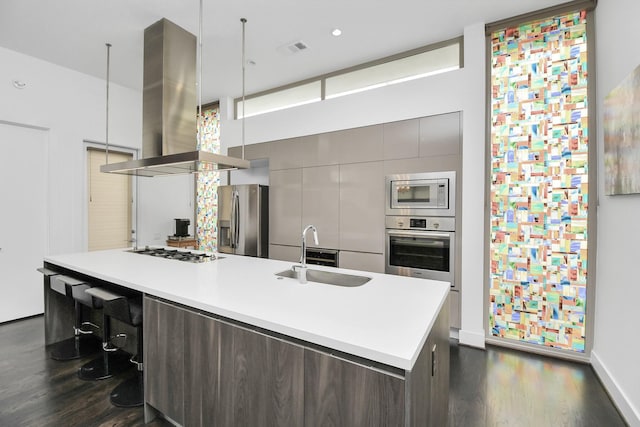 kitchen featuring sink, stainless steel appliances, dark wood-type flooring, island exhaust hood, and a breakfast bar