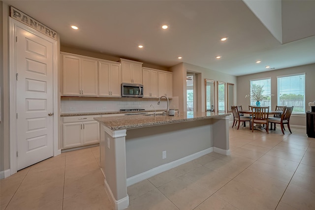 kitchen featuring white cabinets, backsplash, a kitchen island with sink, and sink