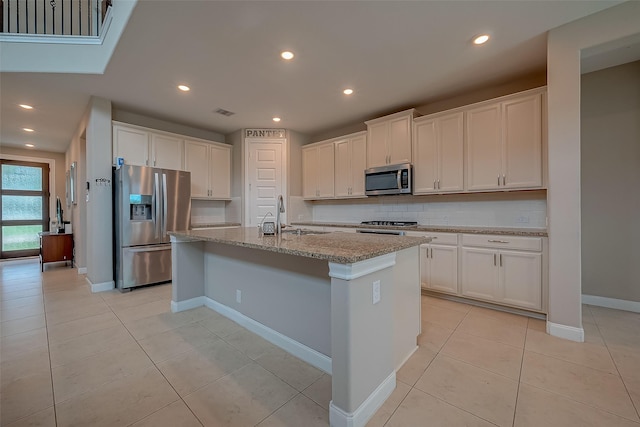 kitchen featuring white cabinets, appliances with stainless steel finishes, and a center island with sink