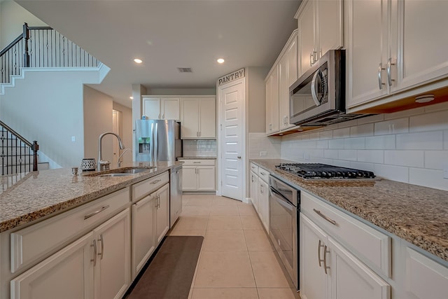 kitchen featuring white cabinetry, light stone countertops, sink, and appliances with stainless steel finishes