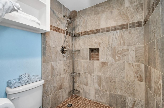 bathroom with a tile shower and toilet