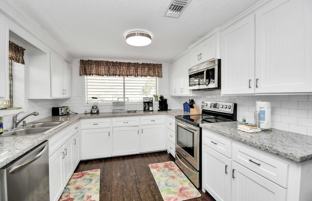 kitchen featuring white cabinets, sink, light stone counters, dark hardwood / wood-style flooring, and stainless steel appliances