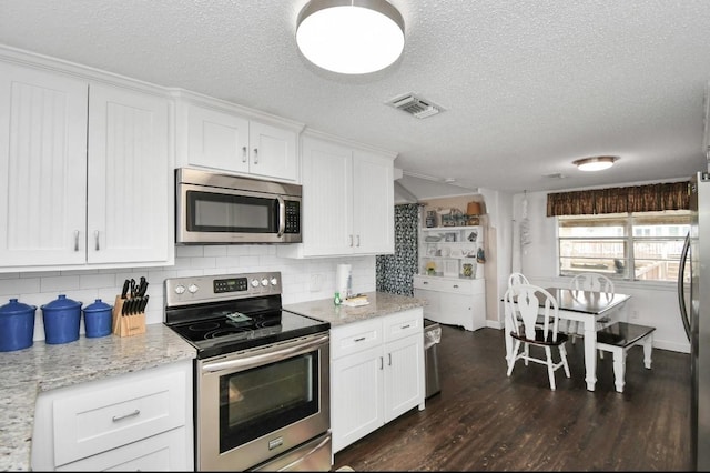 kitchen with white cabinetry, dark hardwood / wood-style flooring, light stone counters, and appliances with stainless steel finishes