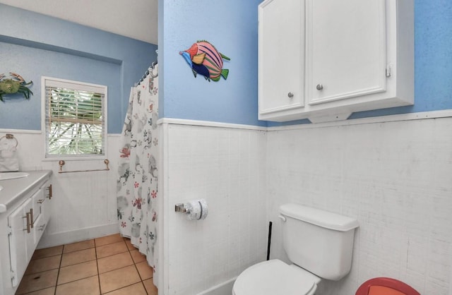 bathroom with tile patterned flooring, toilet, and tile walls