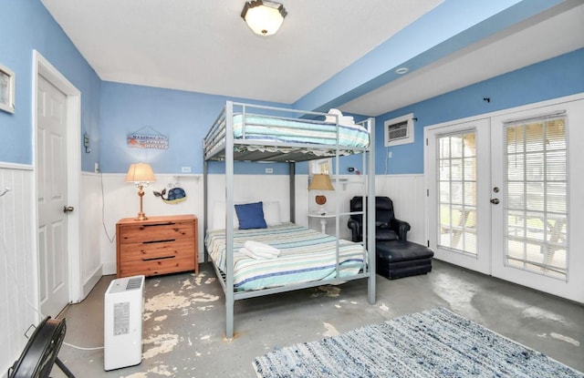 bedroom with a wall unit AC, access to exterior, french doors, and concrete flooring