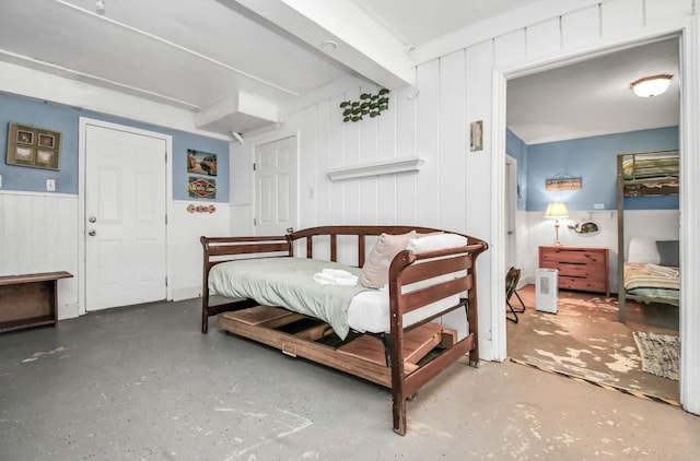 bedroom featuring concrete flooring, beam ceiling, and wooden walls