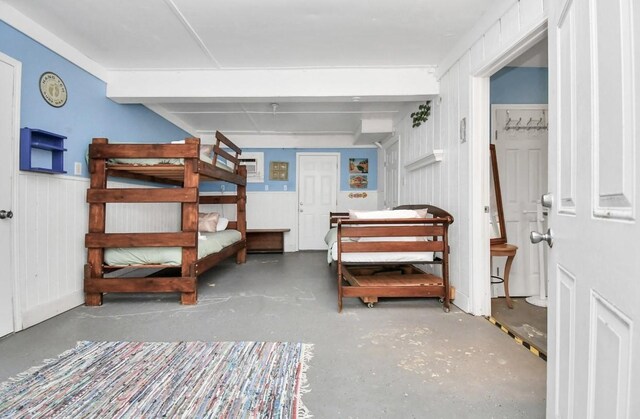 bedroom with concrete floors and wood walls