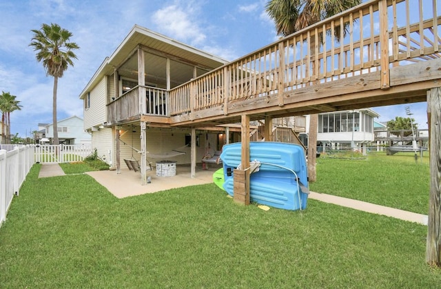 rear view of house featuring a sunroom, a yard, a patio, and a wooden deck