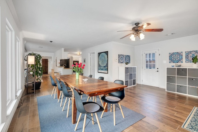 dining area featuring crown molding, visible vents, ceiling fan, and wood finished floors