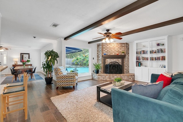 living room with beam ceiling, dark hardwood / wood-style floors, a brick fireplace, and ceiling fan