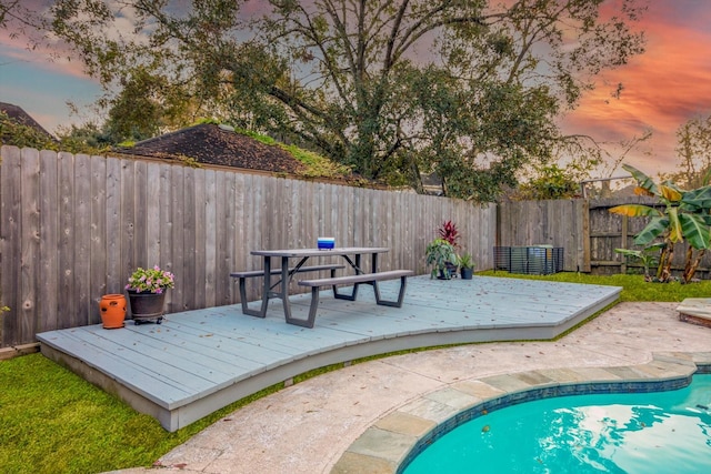 pool at dusk featuring a fenced in pool, a fenced backyard, and a wooden deck