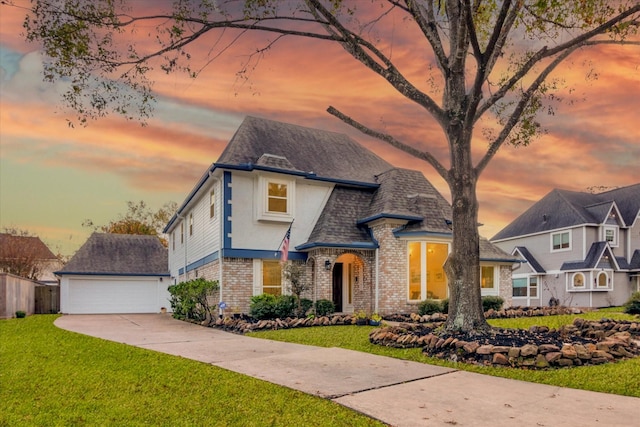 view of front of house featuring brick siding, a detached garage, a shingled roof, a front yard, and fence