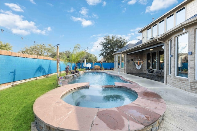 view of swimming pool with a lawn, an in ground hot tub, pool water feature, and a patio