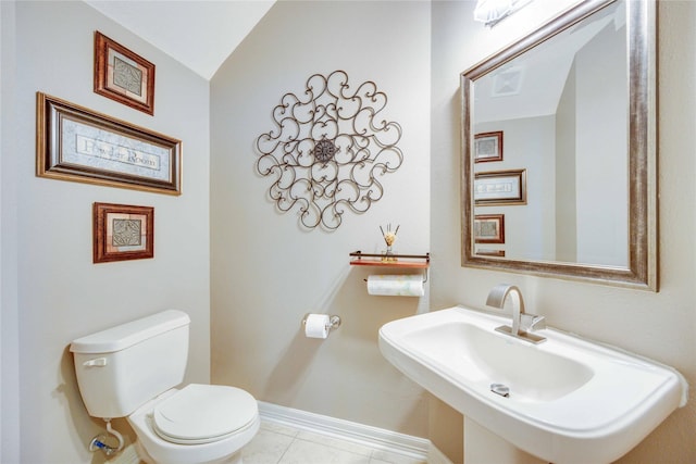 bathroom with tile patterned flooring, toilet, sink, and vaulted ceiling