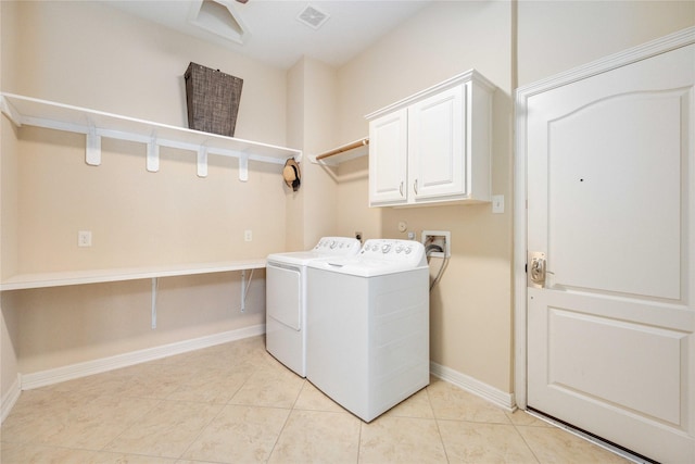 clothes washing area featuring cabinets, washer and dryer, and light tile patterned flooring