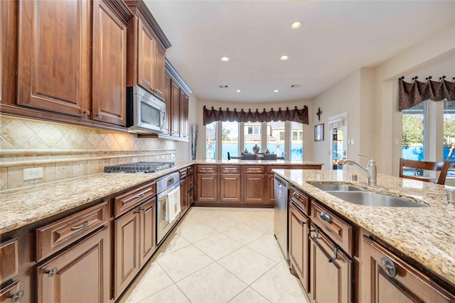 kitchen featuring light stone countertops, backsplash, stainless steel appliances, sink, and light tile patterned floors