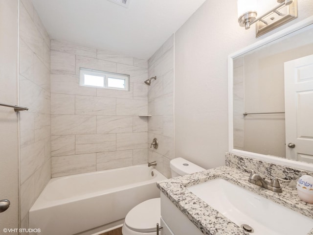 full bathroom featuring vanity, tiled shower / bath, and toilet