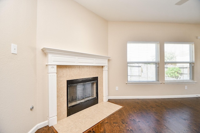 unfurnished living room with dark hardwood / wood-style flooring and a tiled fireplace