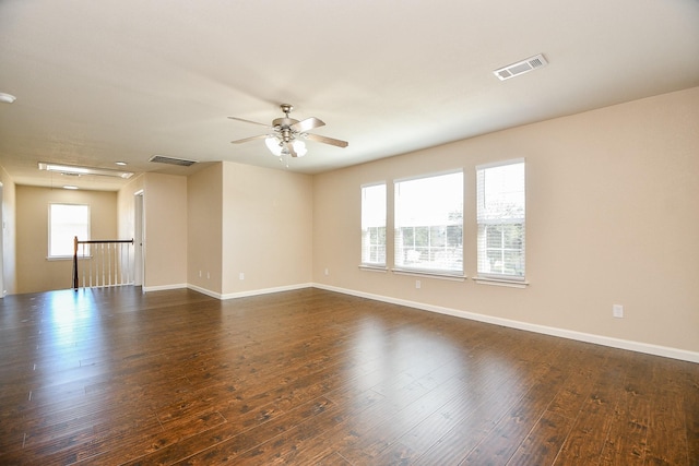 spare room featuring dark hardwood / wood-style flooring, ceiling fan, and a healthy amount of sunlight