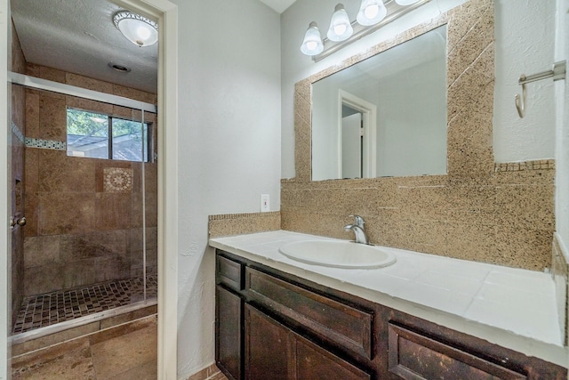 bathroom featuring a tile shower, vanity, and tasteful backsplash