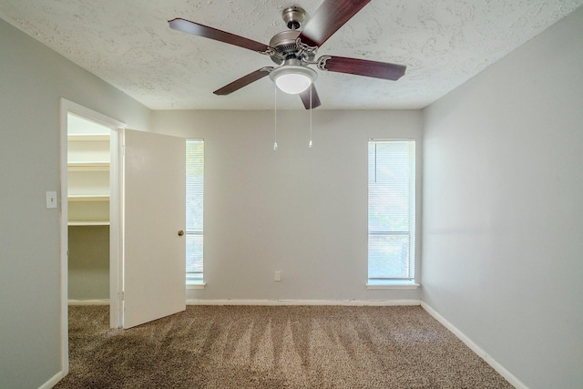 carpeted spare room featuring ceiling fan and a textured ceiling