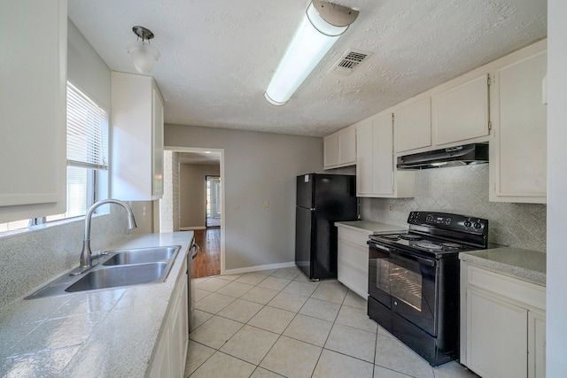 kitchen featuring sink, light tile patterned floors, a textured ceiling, white cabinets, and black appliances