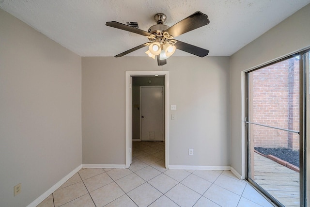 empty room featuring light tile patterned floors, a textured ceiling, and ceiling fan