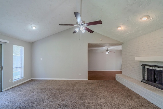 unfurnished living room featuring carpet floors, a textured ceiling, high vaulted ceiling, and a brick fireplace