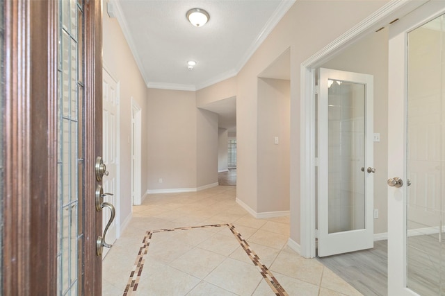 foyer entrance with a textured ceiling, light tile patterned floors, and crown molding