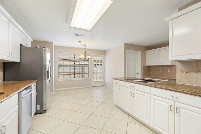 kitchen with pendant lighting, white cabinets, stainless steel dishwasher, decorative backsplash, and a chandelier