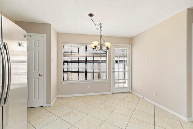 unfurnished dining area featuring a chandelier, light tile patterned floors, and a textured ceiling