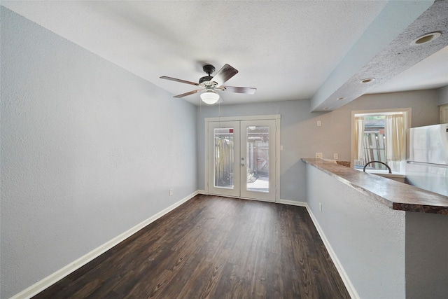 interior space with a textured ceiling, ceiling fan, dark hardwood / wood-style flooring, and french doors