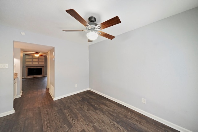 empty room with ceiling fan and dark wood-type flooring