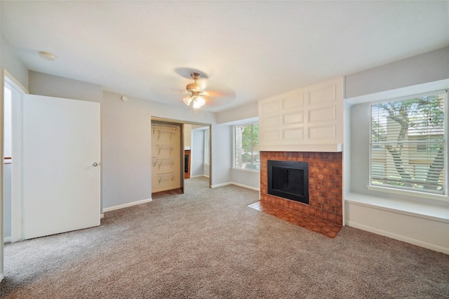 unfurnished living room with ceiling fan, light colored carpet, and a brick fireplace