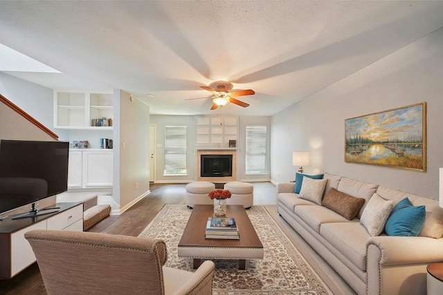 living room featuring ceiling fan, dark hardwood / wood-style flooring, and built in shelves