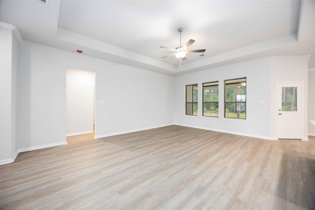 unfurnished room featuring a raised ceiling, ceiling fan, and light hardwood / wood-style flooring