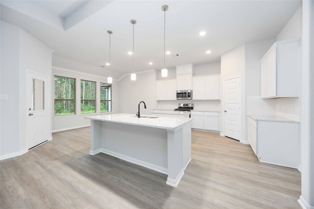 kitchen featuring stainless steel appliances, white cabinetry, a center island with sink, and light hardwood / wood-style floors