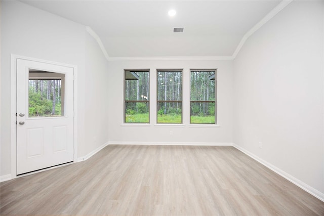 unfurnished room featuring light hardwood / wood-style floors, lofted ceiling, and ornamental molding