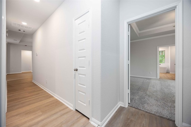 corridor with ornamental molding and light hardwood / wood-style flooring