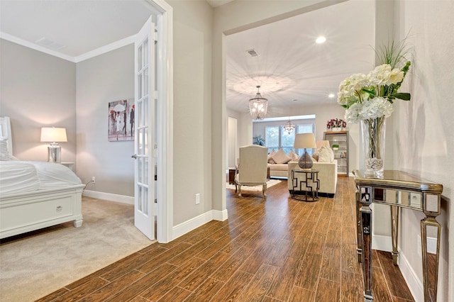 bedroom featuring hardwood / wood-style floors, a notable chandelier, ornamental molding, and french doors