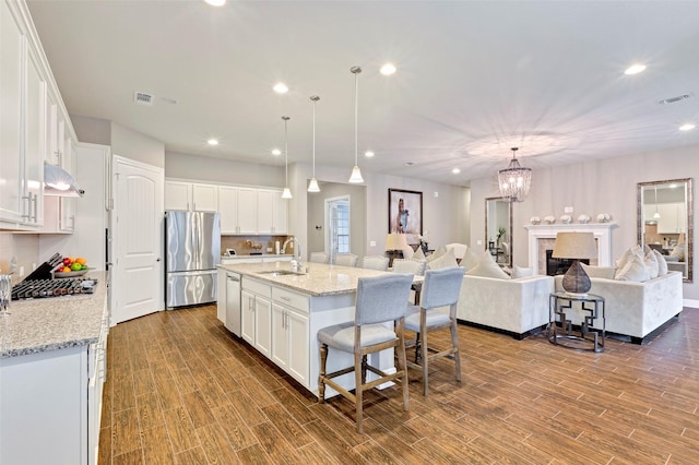 kitchen featuring white cabinetry, a center island with sink, hardwood / wood-style floors, and appliances with stainless steel finishes