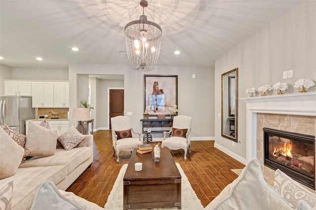 living room featuring a tiled fireplace, a chandelier, and dark hardwood / wood-style floors