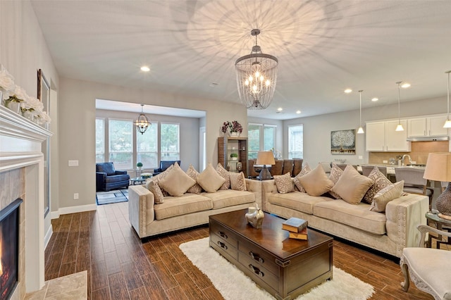 living room featuring a fireplace, dark hardwood / wood-style flooring, an inviting chandelier, and a wealth of natural light