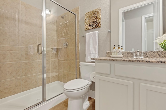 bathroom featuring tile patterned flooring, vanity, toilet, and a shower with door