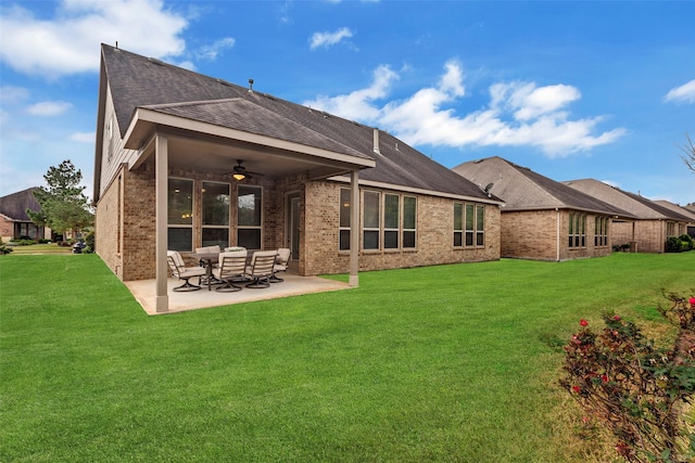 rear view of property with ceiling fan, a patio area, and a yard