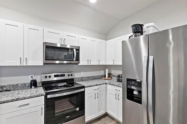 kitchen featuring light stone countertops, white cabinetry, stainless steel appliances, and vaulted ceiling