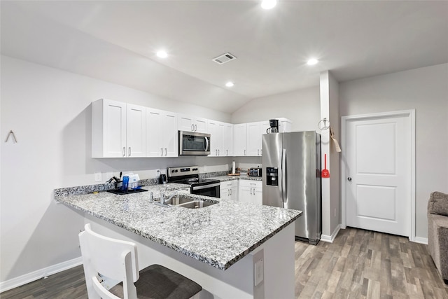 kitchen featuring a breakfast bar area, kitchen peninsula, stainless steel appliances, and lofted ceiling